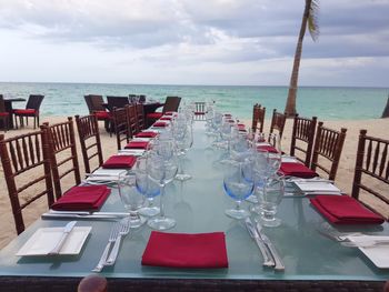 Chairs and tables at beach against sky