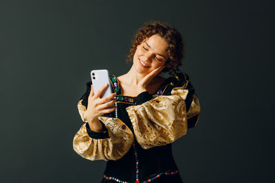 Young woman using mobile phone against black background