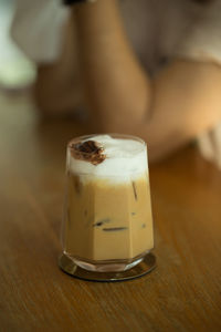 Cropped hand of woman holding coffee on table