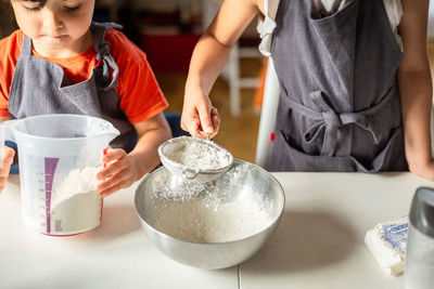 Two girls wearing grey aprons preparing to bake