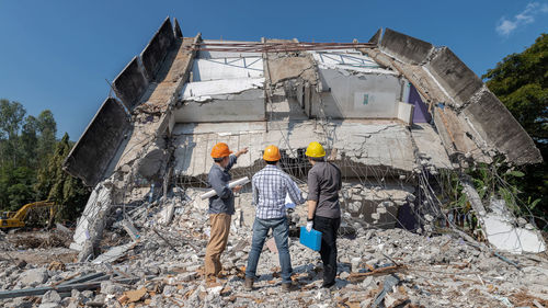 Rear view of people at construction site against sky