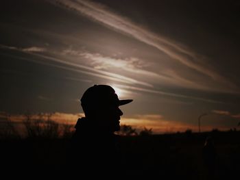 Silhouette man on field against sky during sunset