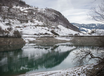 Scenic view of lake by snowcapped mountains against sky