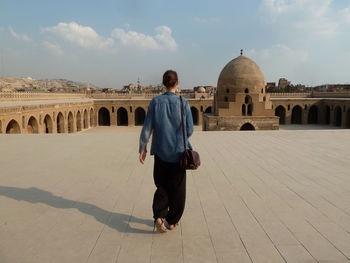 Rear view of tourist walking at mosque of ibn tulun against sky