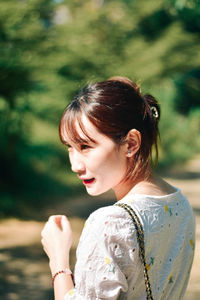 Side view of young woman looking away while standing outdoors