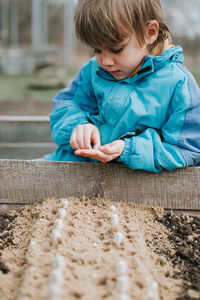 Spring planting seeding farm garden. little kid boy farmer gardener plants sow vegetable seeds soil