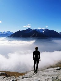 Rear view of man standing on snowcapped mountain