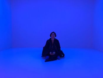 Woman sitting against blue background