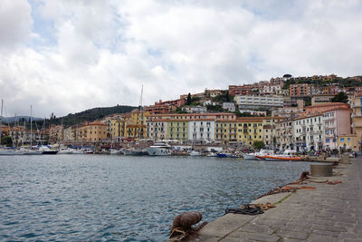 City at waterfront against cloudy sky