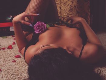 Sensuous woman with rose lying down on rug