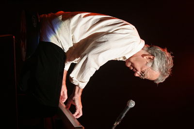 Side view of man standing against black background