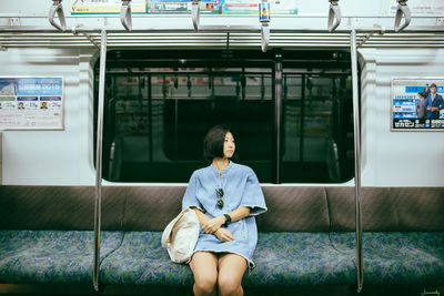 Full length portrait of woman sitting on train