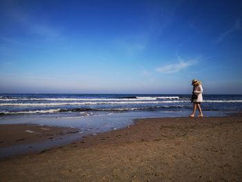 Woman standing on beach against sky