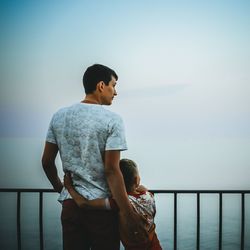 Rear view of man looking at sea against sky