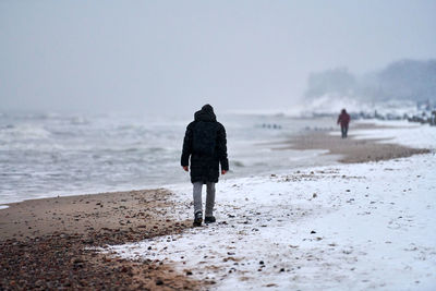 Rear view of people walking on beach