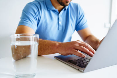 Man working laptop hands glas of water on the desk