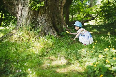Girl by tree trunk on field