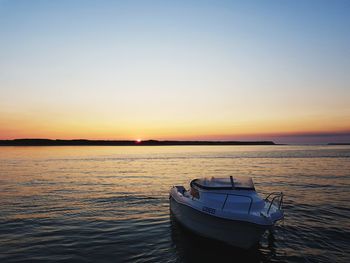 Boat moored on sea against sky during sunset