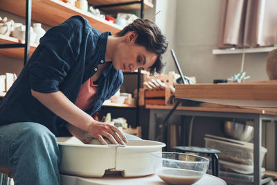 A woman in a pottery workshop works on a potter's wheel