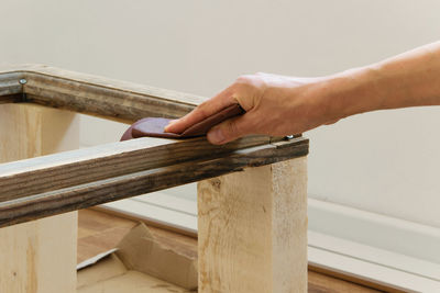 Close-up of hand polishing wood against wall