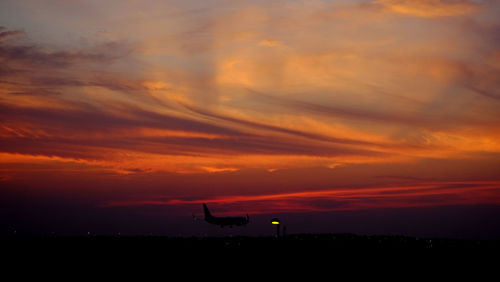 Scenic view of silhouette field against dramatic sky during sunset