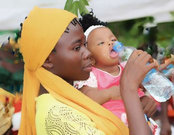 Side view of woman feeding water to daughter