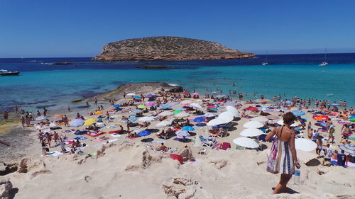 People on beach against clear blue sky