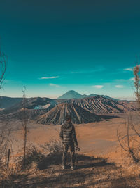 Rear view of man standing at landscape against sky