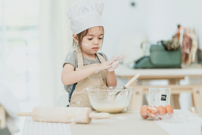 Midsection of baby girl in bowl on table at home