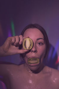 Portrait of young woman holding kiwi