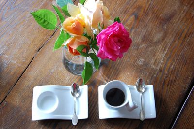 Close-up of roses in vase on table and coffe aside