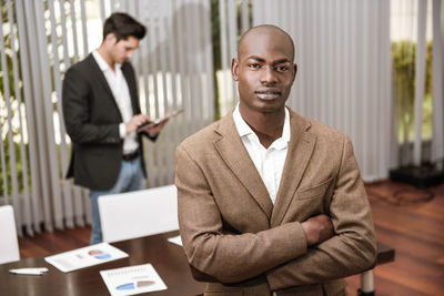 Portrait of businessman standing with colleague in office 