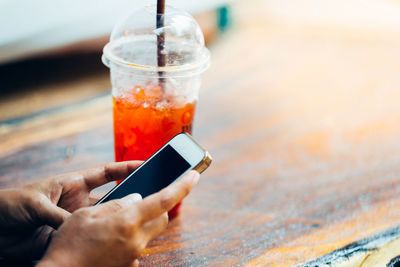 Midsection of man holding mobile phone on table