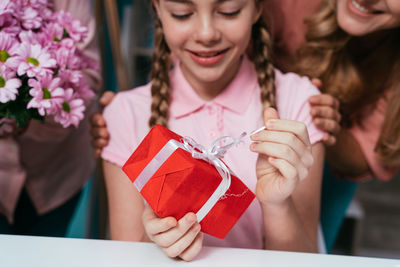 Midsection of family standing by girl opening gift at home