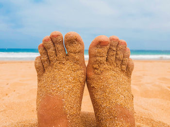 Low section of person covered with sand at beach