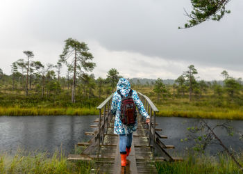 Rear view of woman standing by lake