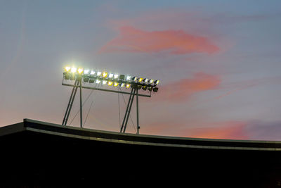 Glowing stadium lights against sunset sky during blue hour