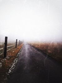 Road in foggy weather against sky during winter