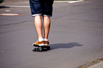 Low section of man skateboarding on road