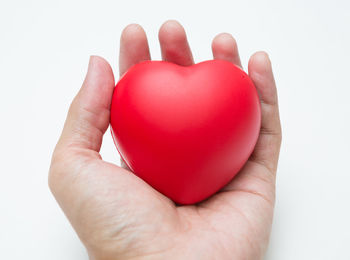 Close-up of hand holding heart shape over white background