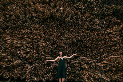 Woman with arms outstretched standing against trees