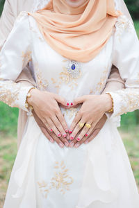 Midsection of woman holding white flower