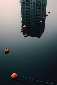High angle view of buoys on calm lake with building reflection
