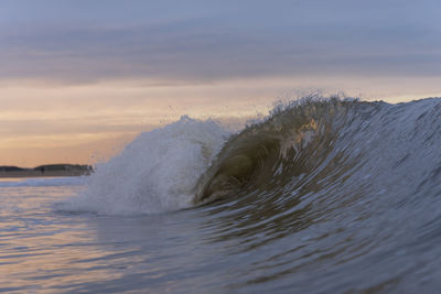 Sea waves splashing against sky during sunset