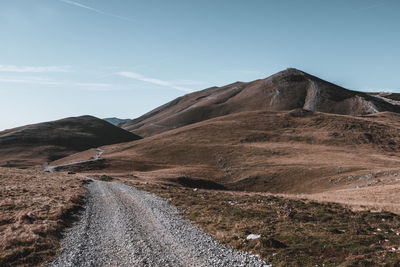 Scenic view of road by mountains against sky