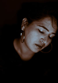 Close-up portrait of young woman against black background