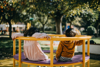 Rear view of kids sitting on play equipment