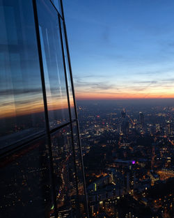 Illuminated cityscape against sky at sunset