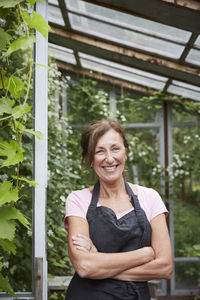 Portrait of confident female gardener standing arms crossed at yard