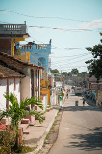 Road by buildings in city against sky